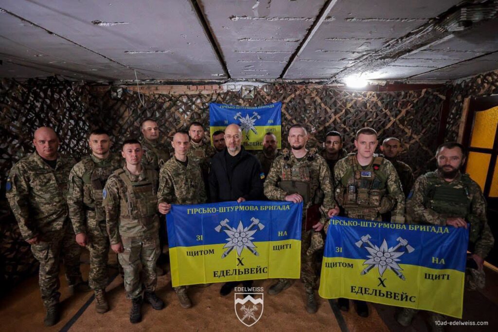 Військові з прапорами гірсько-штурмової бригади Едельвейс