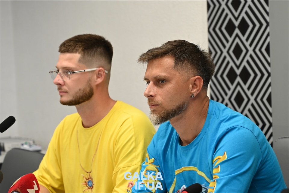 Двоє чоловіків на пресконференції в яскравих футболках.