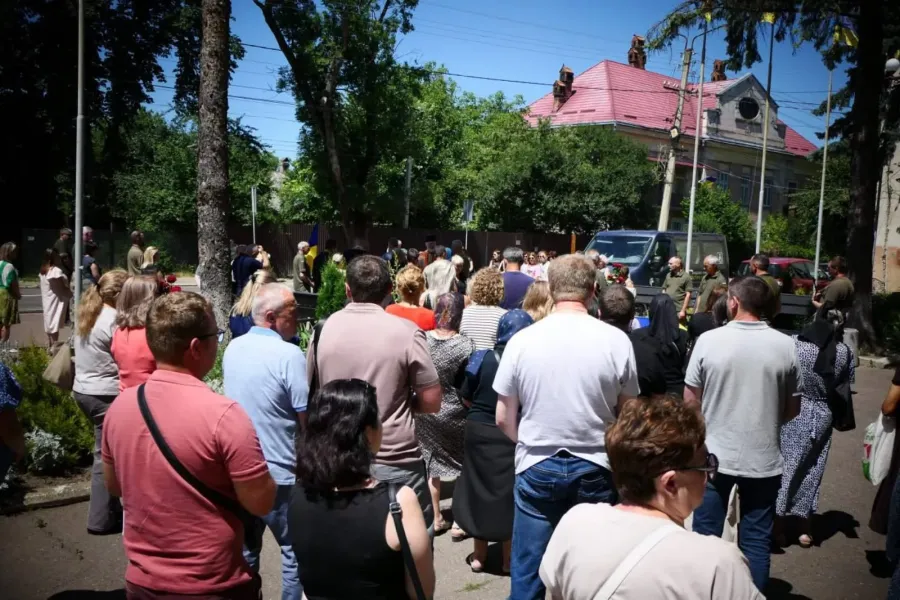 Натовп людей на вулиці біля будівлі.