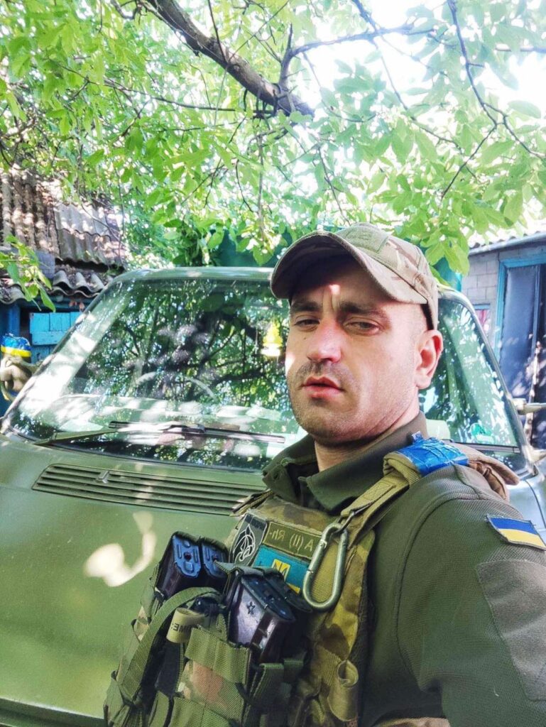 Військовий у формі біля зеленого авто