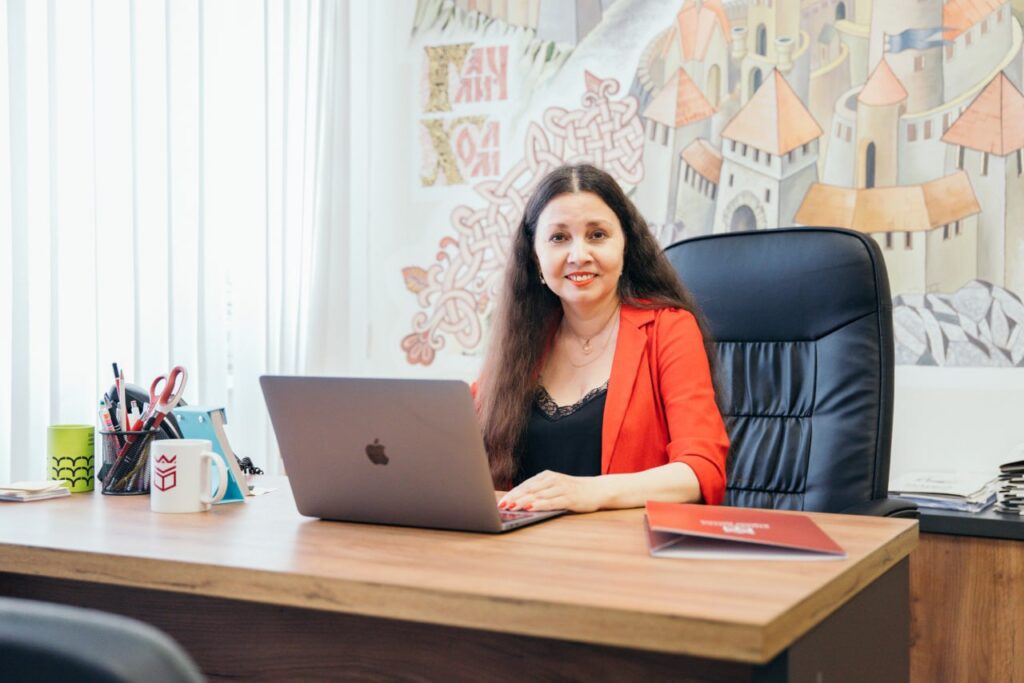 Жінка в офісі з ноутбуком і чашкою