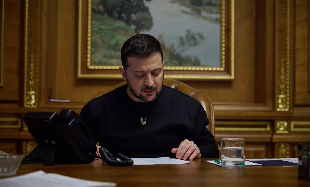 Людина за столом з телефоном та документами.