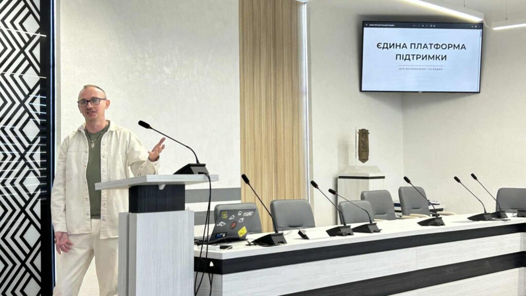 Чоловік виступає на конференції, екран з текстом.