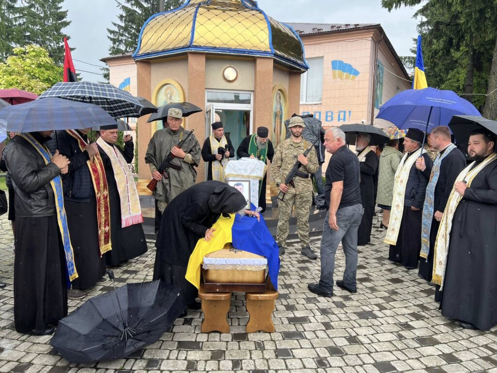 Поминальна церемонія у дощ, релігійні та військові учасники.