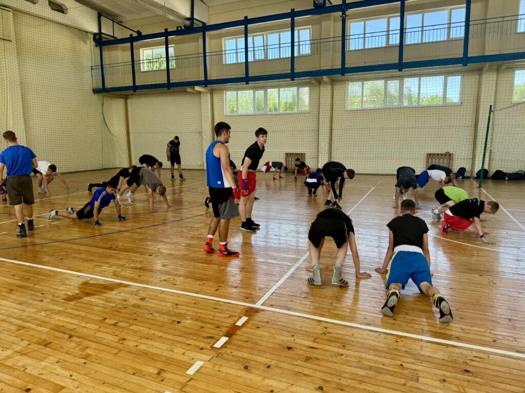 Групове тренування у спортивному залі, люди на підлозі.