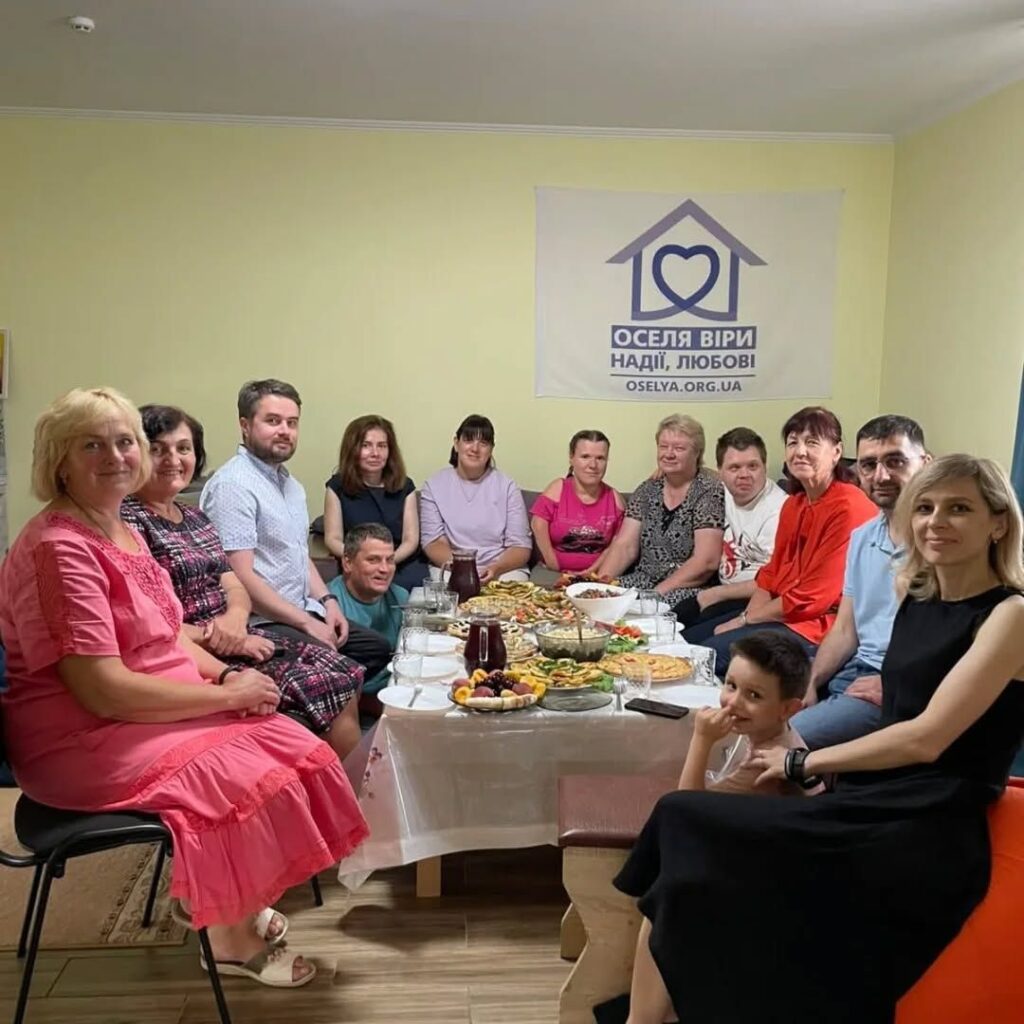 Люди навколо столу з їжею в кімнаті.