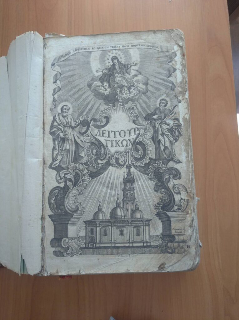 Старовинна книга з релігійною ілюстрацією на обкладинці.
