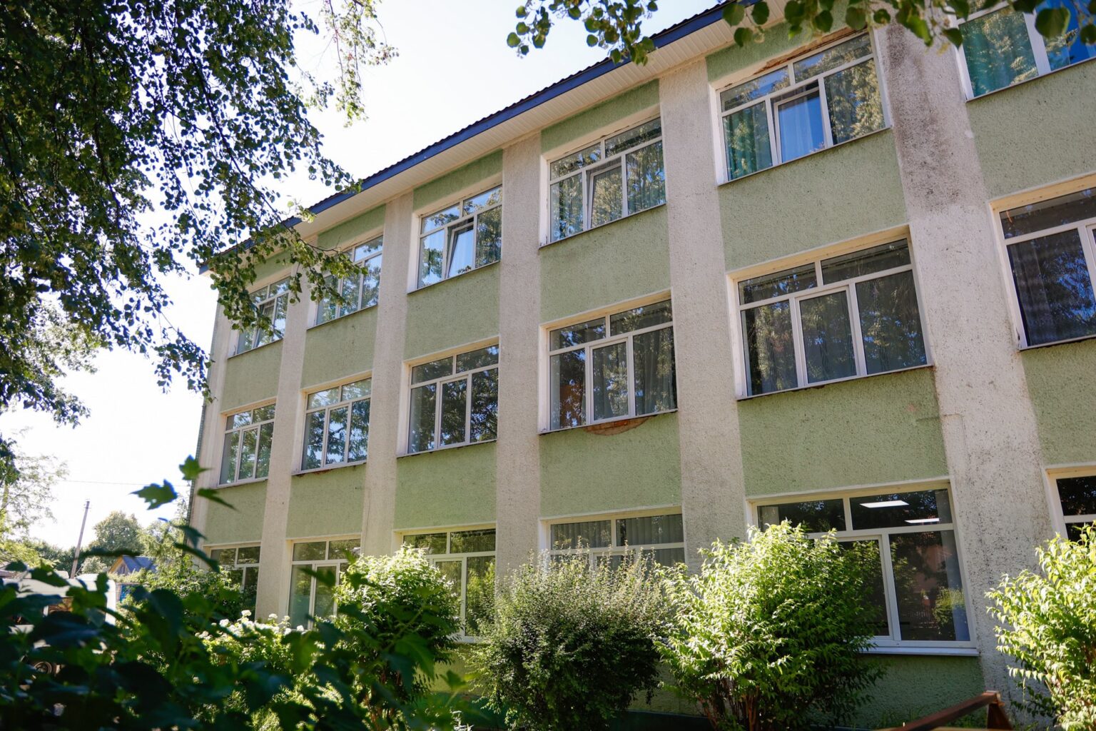 Зелена будівля з деревами на передньому плані