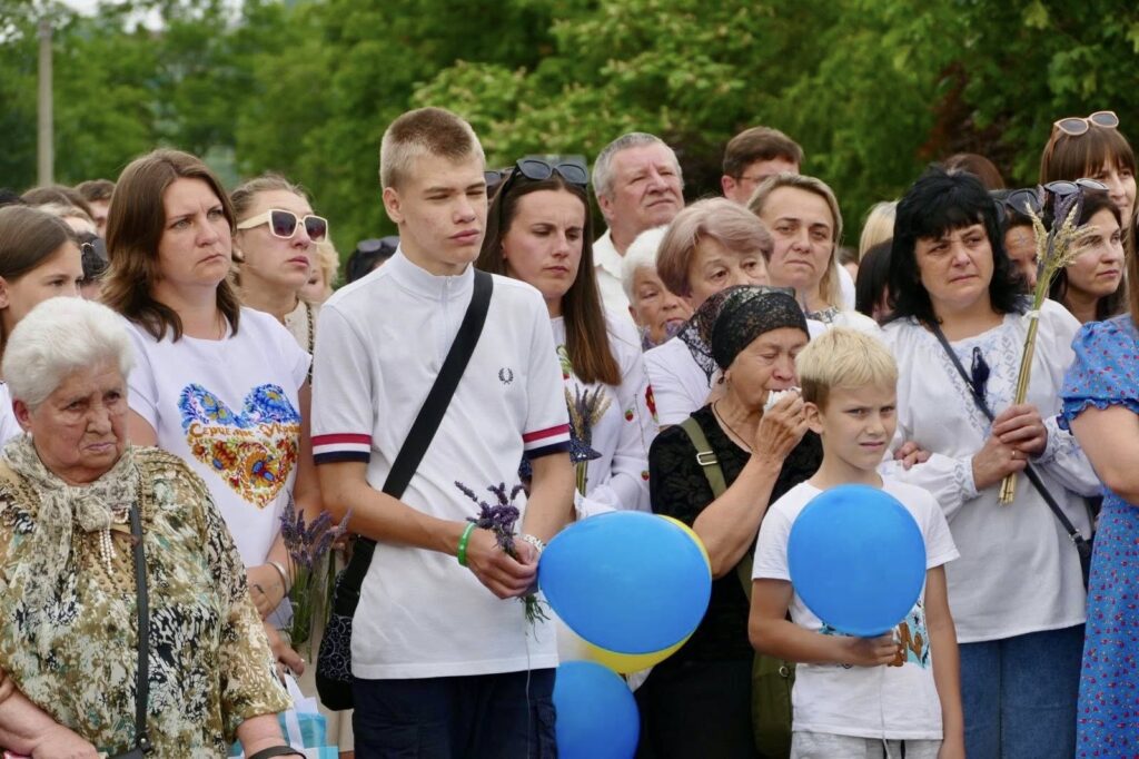 Група людей із жовто-блакитними кульками на вулиці.