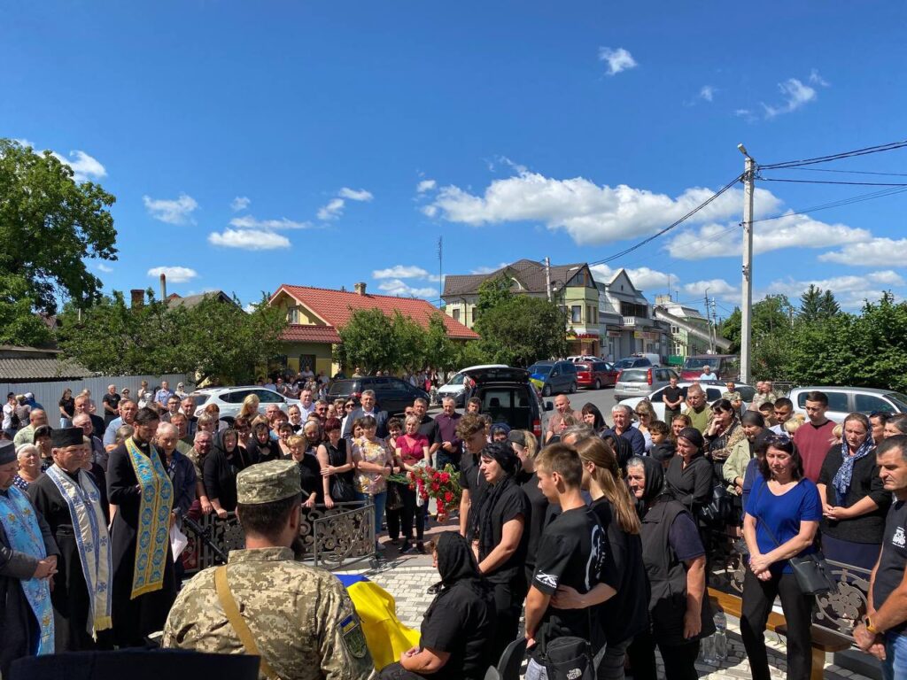 Люди на церемонії прощання під відкритим небом.