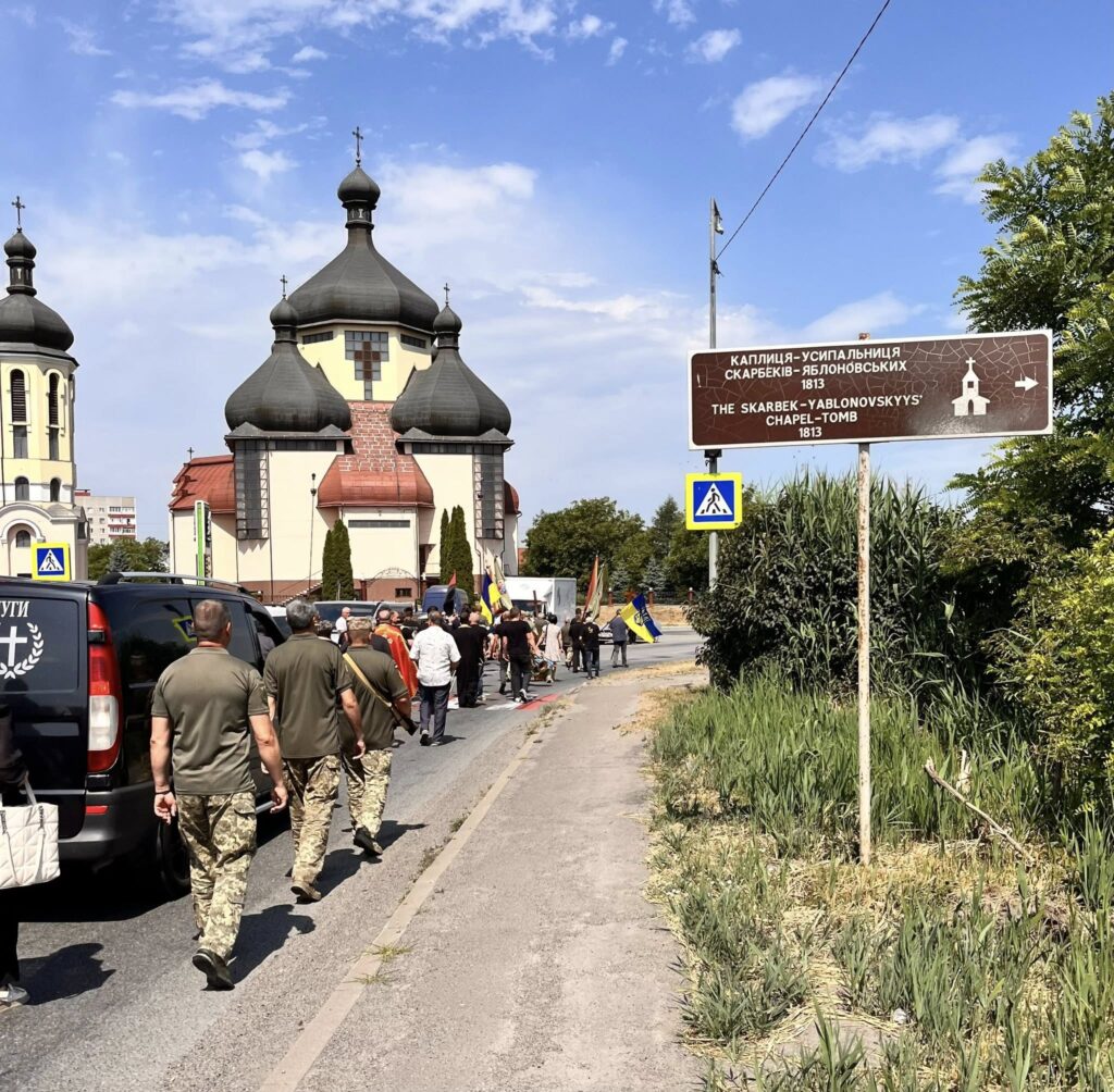 Люди біля церкви зі знаком на дорозі.