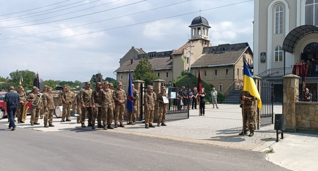 Військові на заході біля церкви з прапором.
