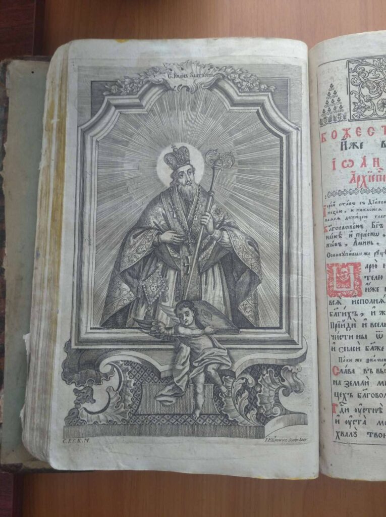 Гравюра святого у релігійній книзі, ангел унизу.