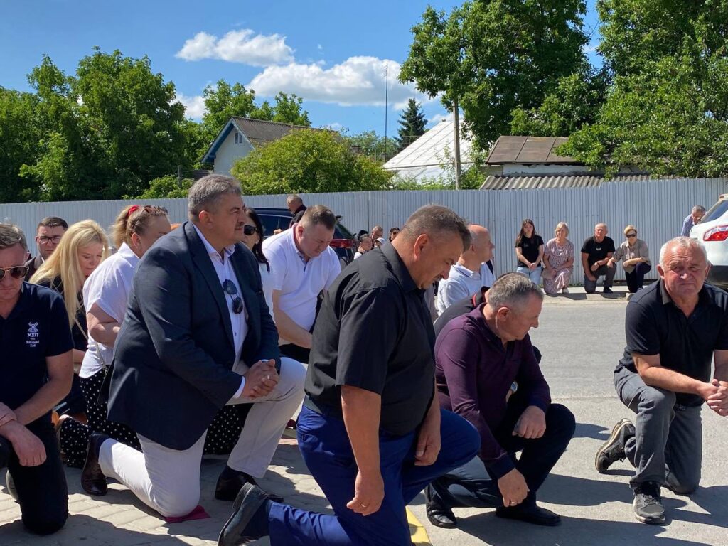 Люди на колінах на вулиці в сонячний день.
