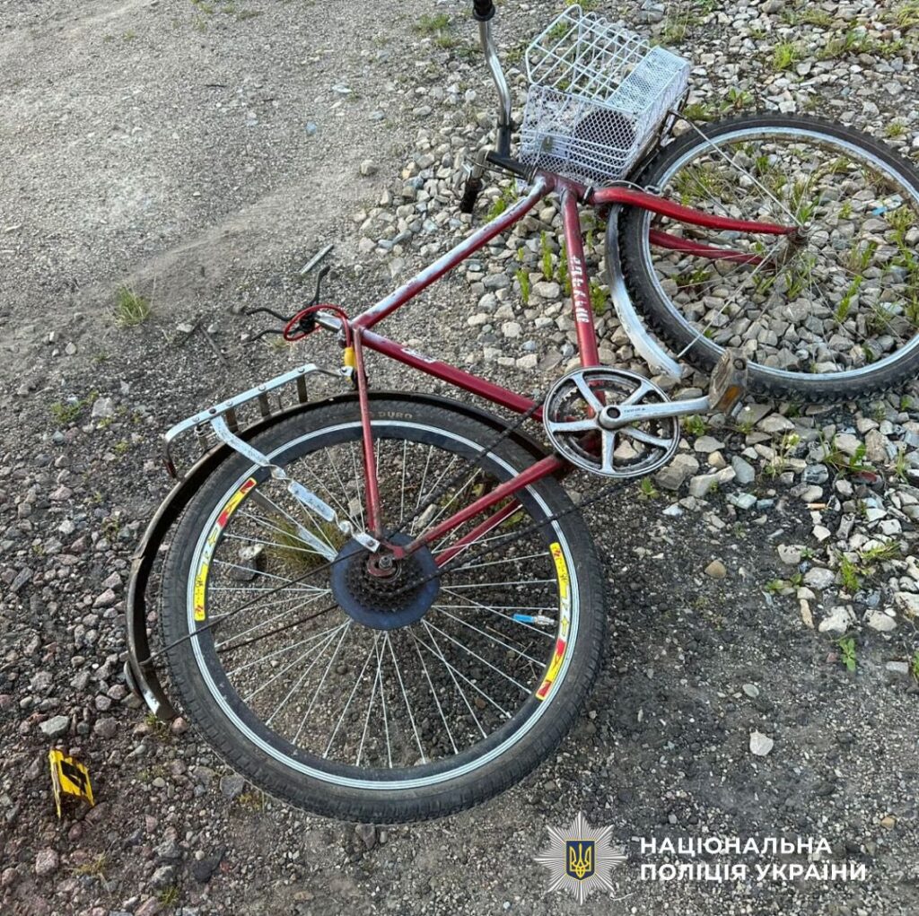 Пошкоджений червоний велосипед на дорозі з камінням.