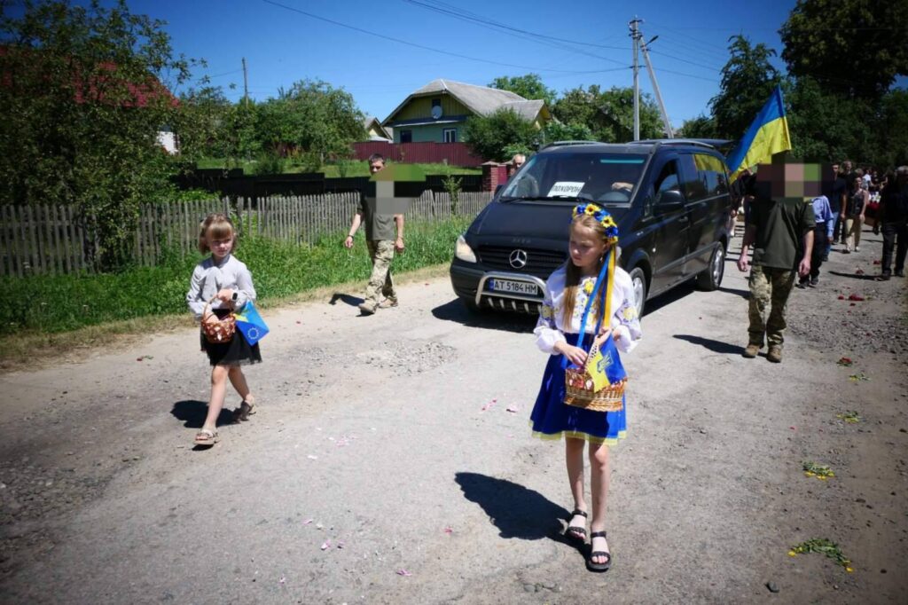 Діти на вулиці з прапорами та корзинами.