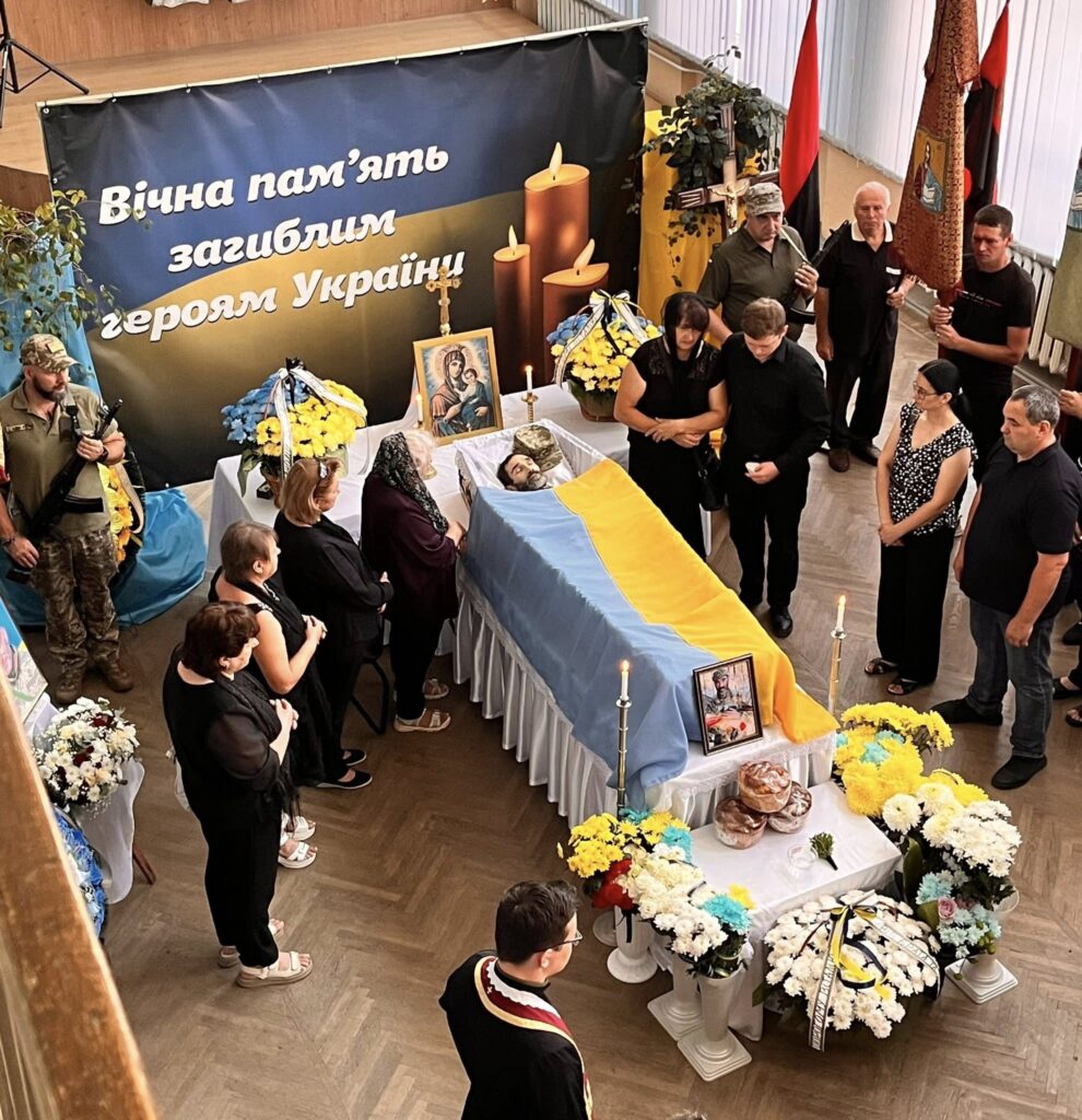 Похоронна церемонія з українським прапором і вінками.