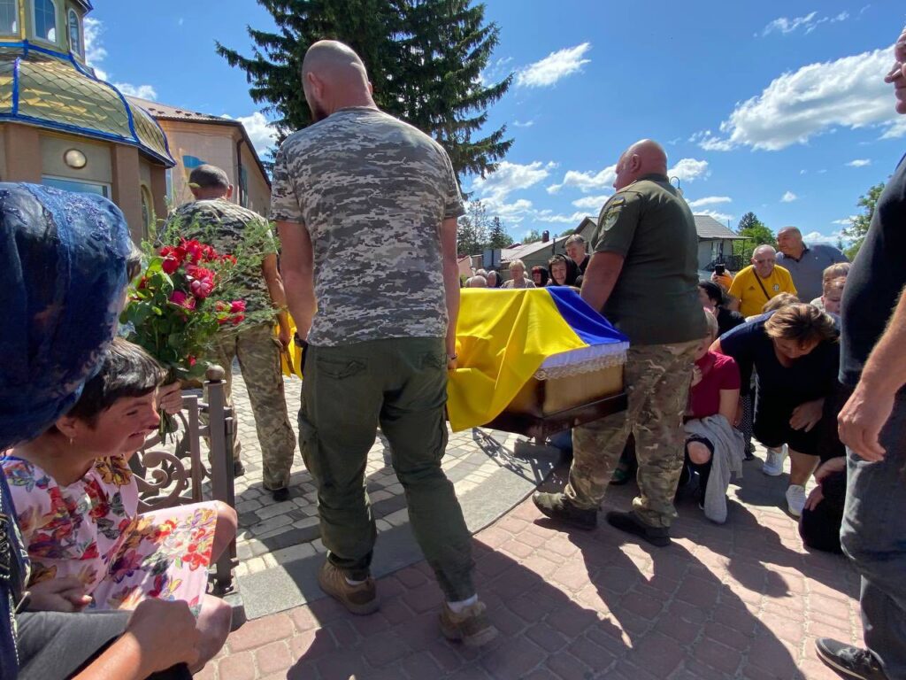 Похорон з українським прапором, люди в скорботі.
