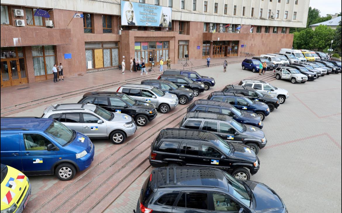 Автомобілі припарковані перед великою будівлею, прапори ЄС