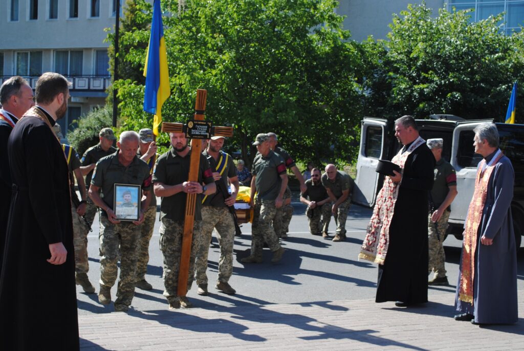 Військова похоронна процесія з українським прапором.
