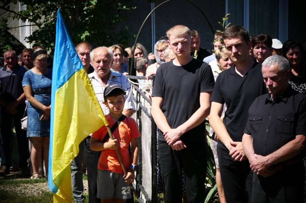 Люди з прапором України на вулиці вдень.