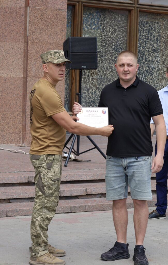 Військовий вручає подяку чоловікові, церемонія нагородження.