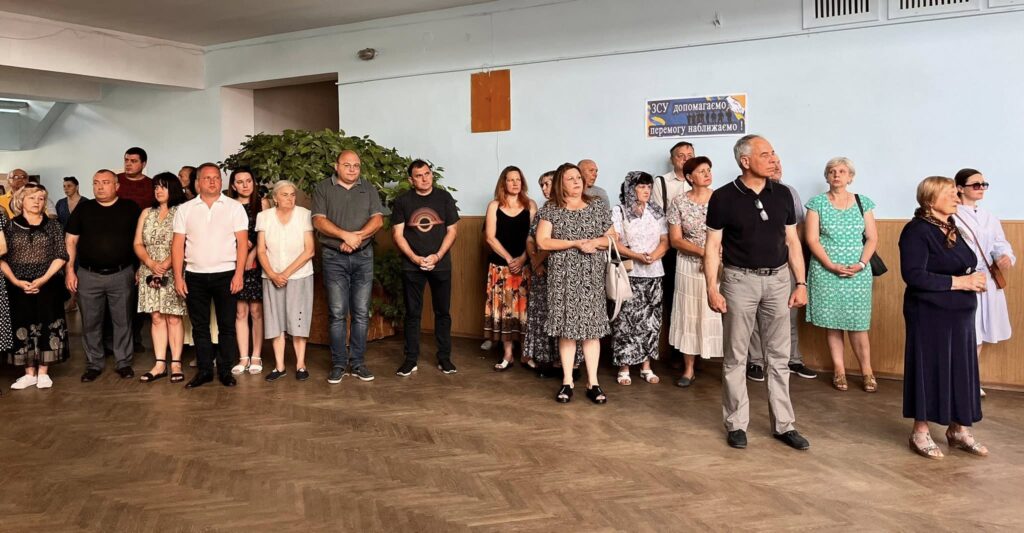 Група людей стоїть у приміщенні, дивляться вперед.