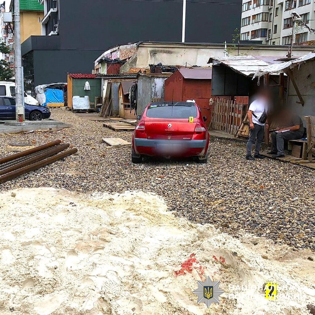 Червоний автомобіль на гравійній дорозі біля будівель