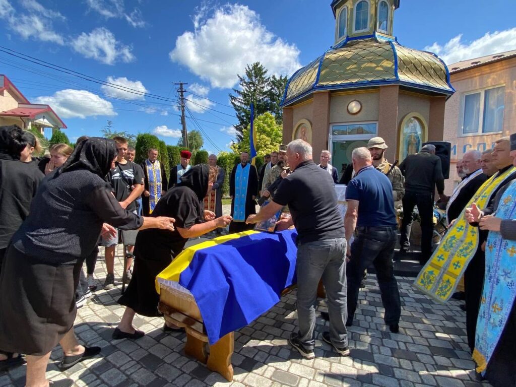 Прощання з солдатом біля церкви під прапором України.