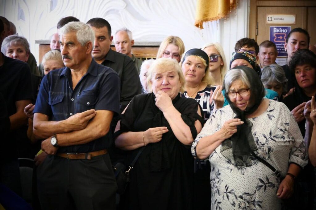 Люди на похороні в приміщенні.