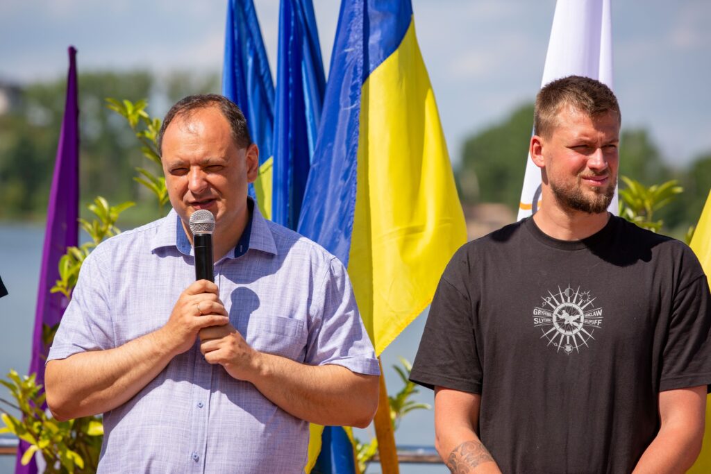 Чоловік з мікрофоном на фоні прапора України