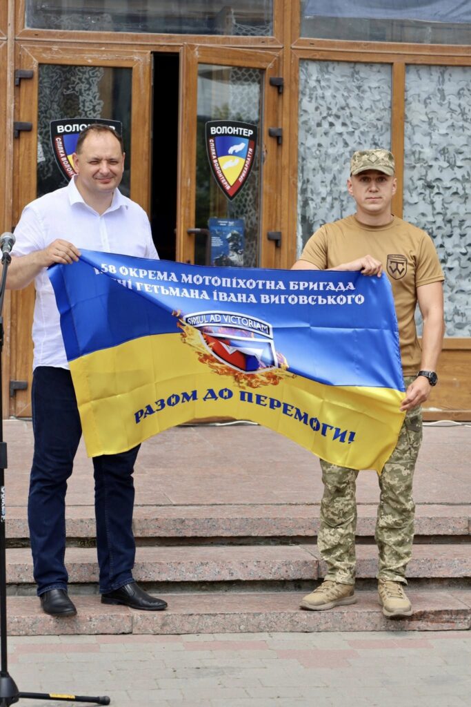 Двоє чоловіків тримають прапор військової бригади