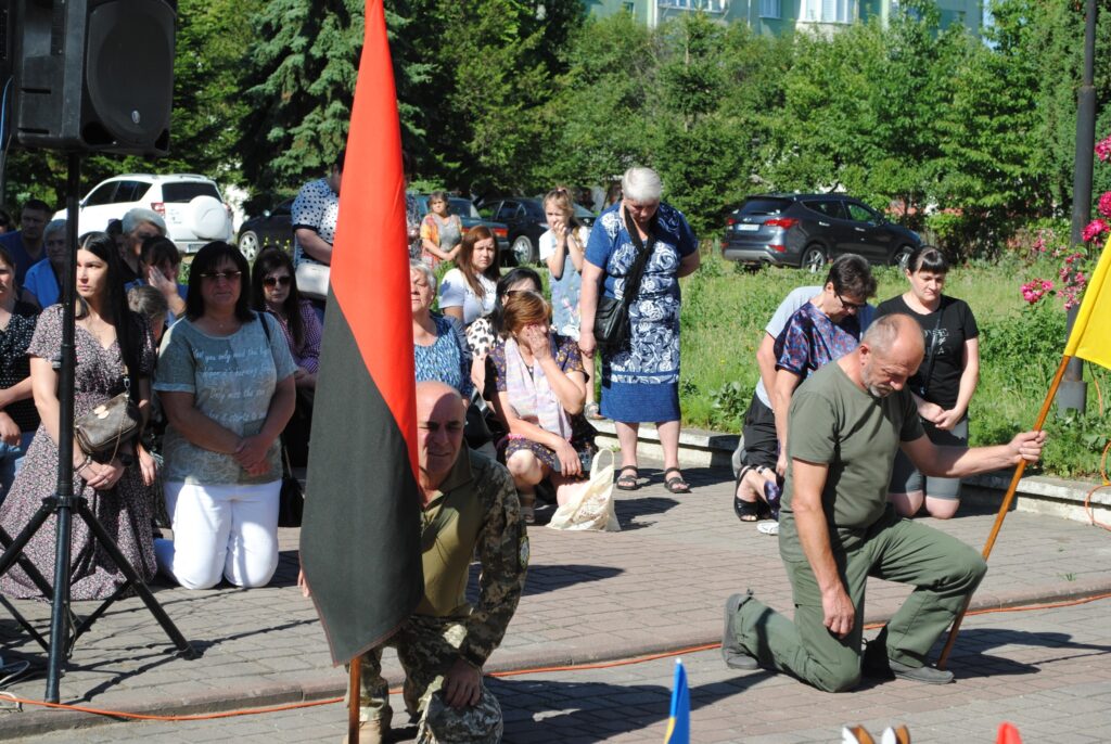 Люди на вулиці з червоно-чорним прапором.
