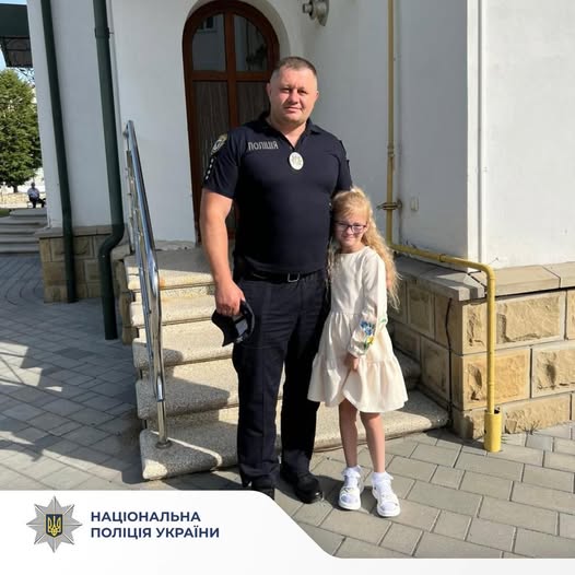 Поліцейський і дитина біля будівлі поліції
