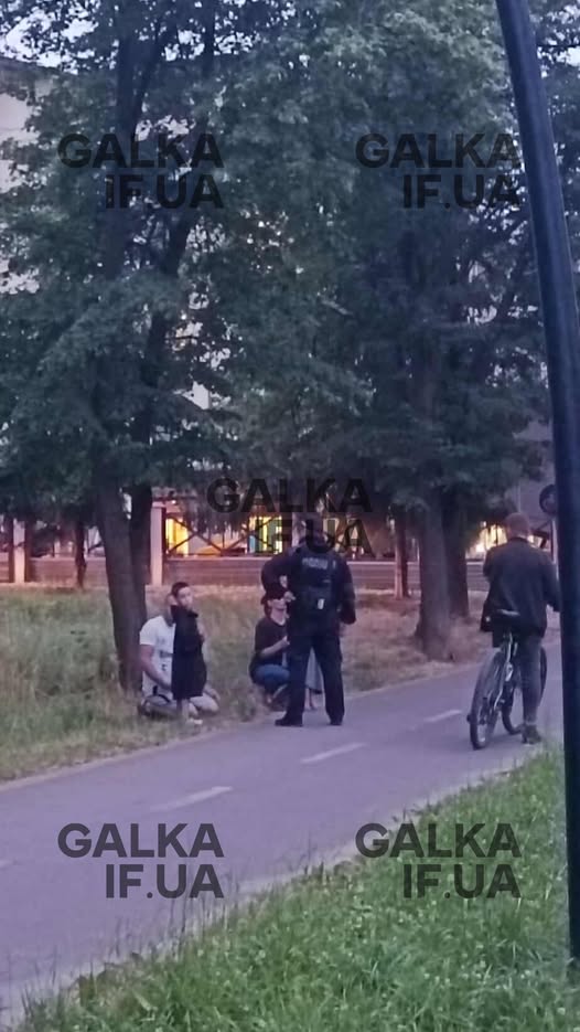 Поліцейський розмовляє з людьми в парку, вечір.