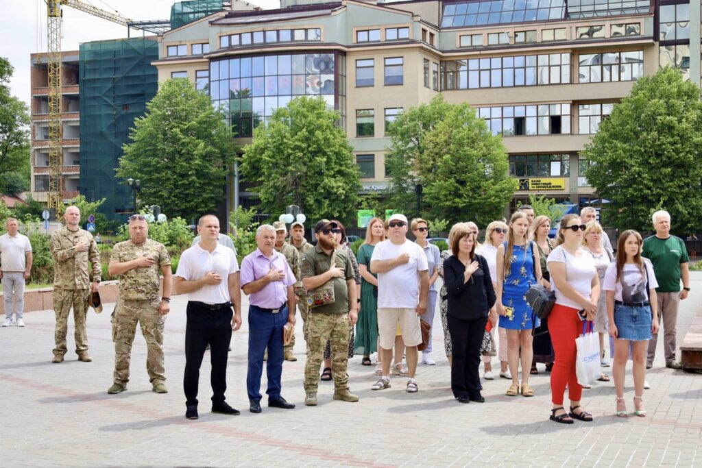 Люди на вулиці перед будівлею, патріотичний захід.