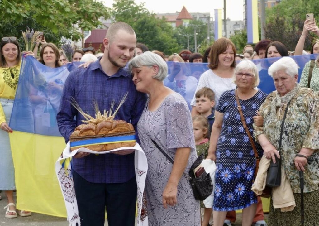 Люди на вулиці з хлібом і українським прапором