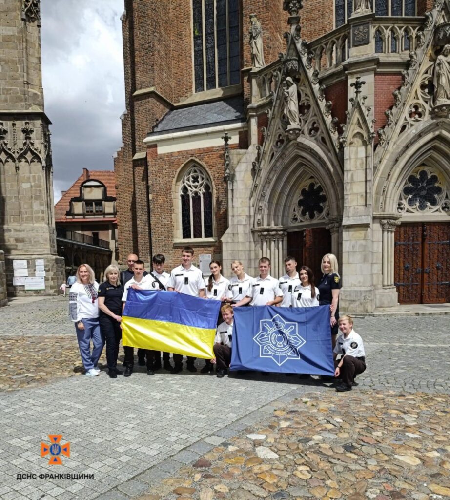 Люди тримають український та інший прапори біля церкви.