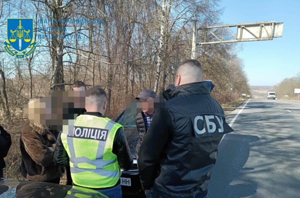 Поліцейські та СБУ розмовляють з людьми на дорозі.