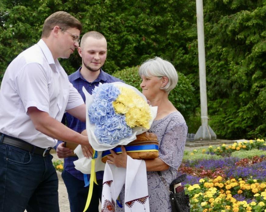 Люди з квітами на вулиці, літня жінка.