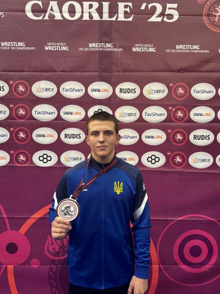 Спортсмен з медаллю на фоні банера Caorle'25.