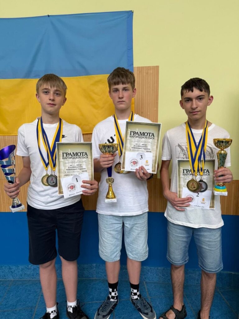 Три юнаки з нагородами: кубки та медалі