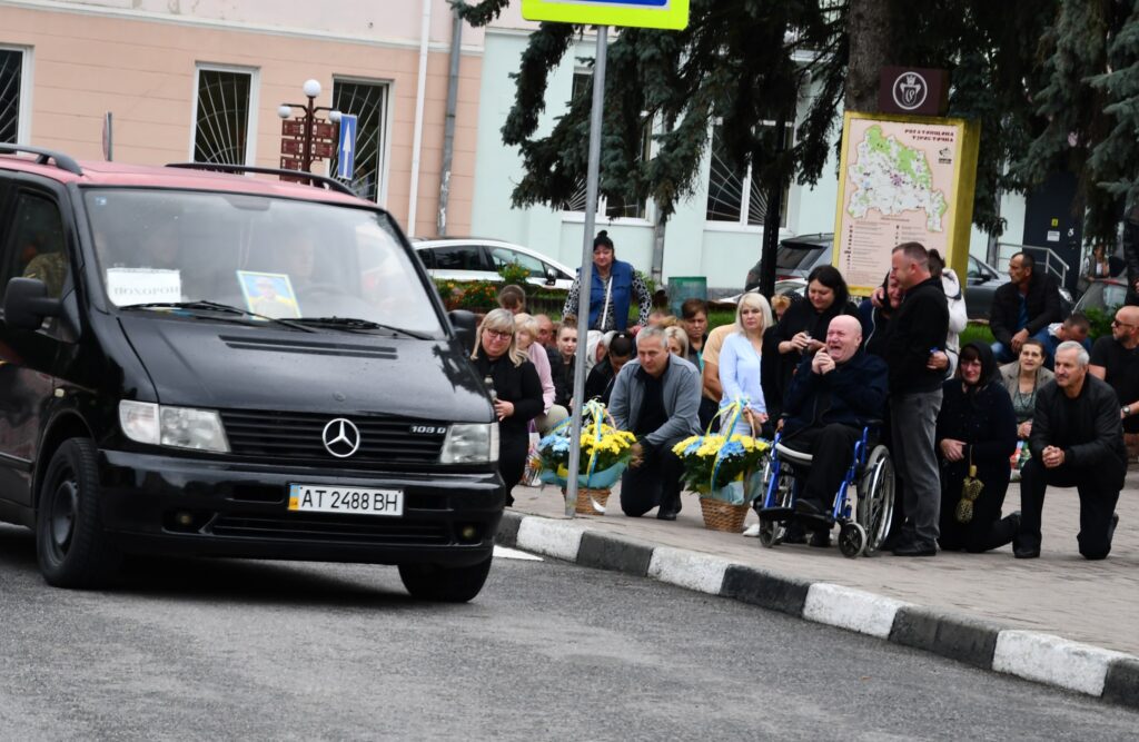Люди на похоронній процесії з автомобілем.
