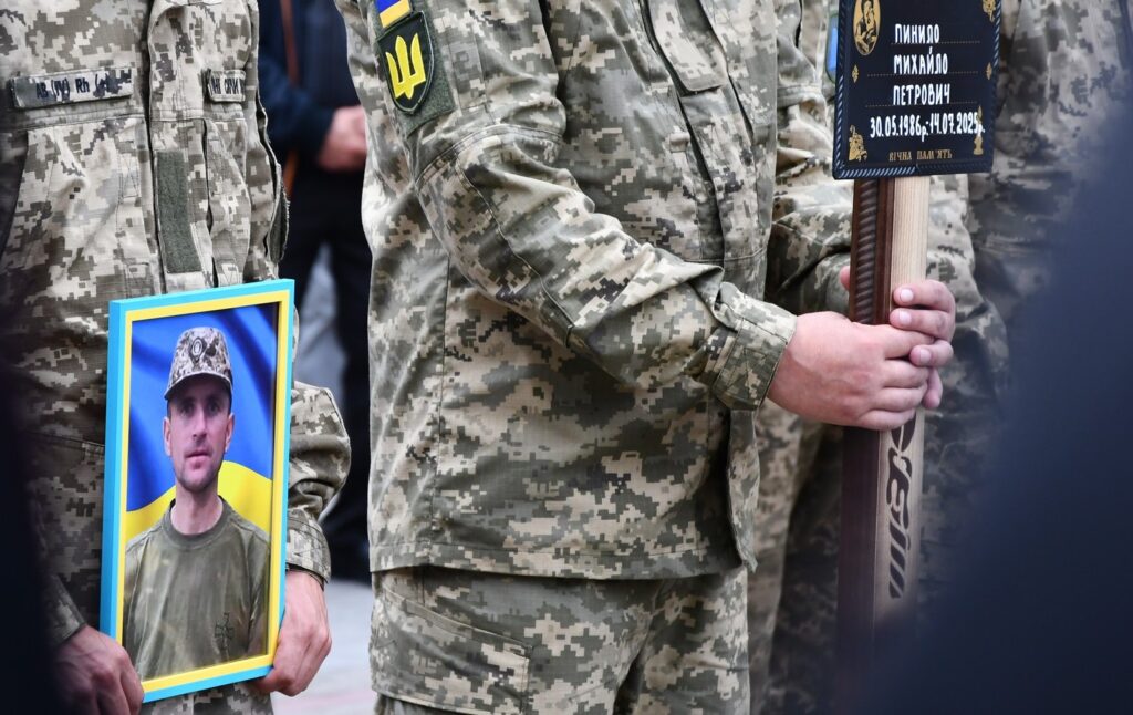 Українські військові тримають портрет полеглого товариша.