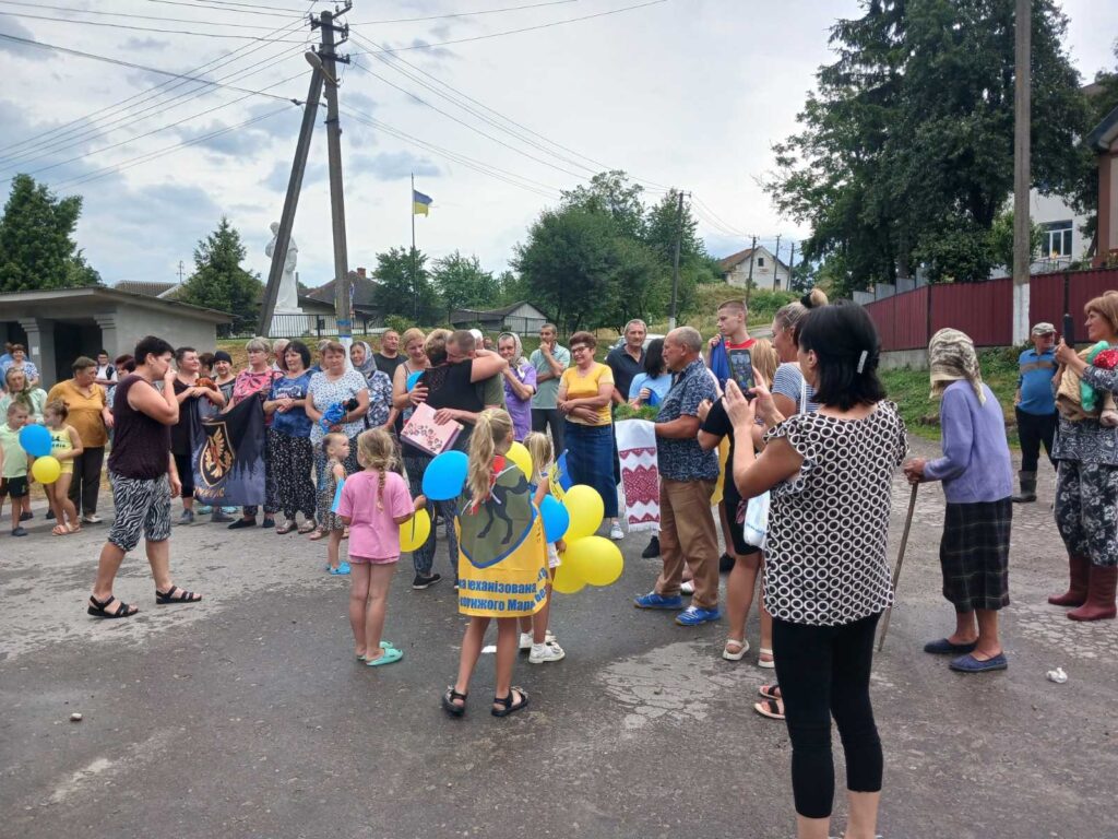 Люди на вулиці святкують з прапорами та кульками.