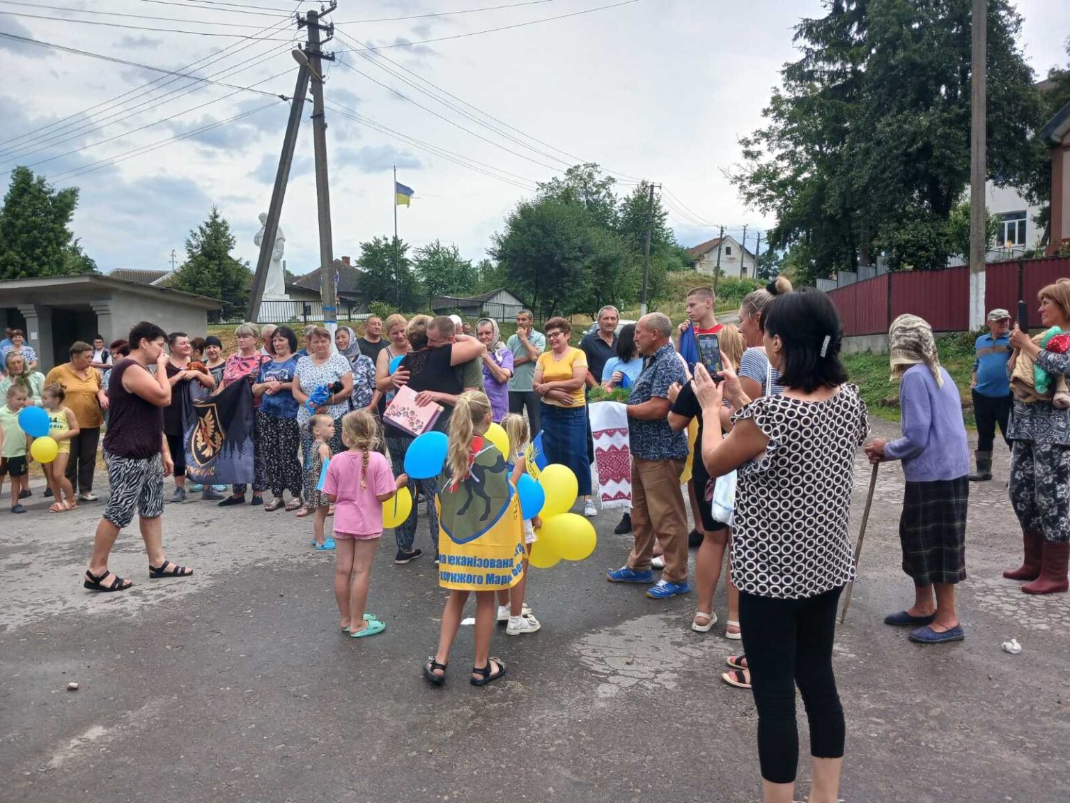 Група людей на вулиці з прапорами і кульками.