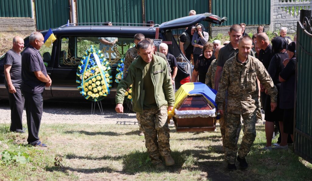 Військові несуть труну на похороні з вінками