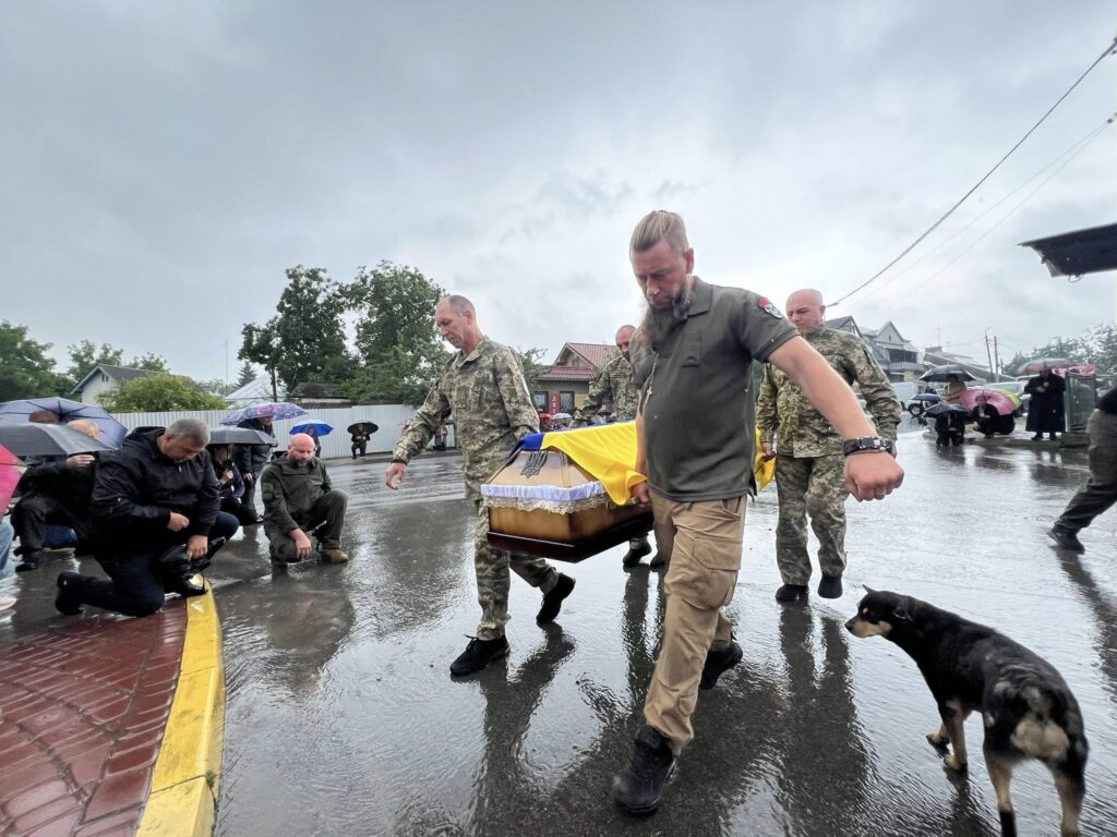 Похоронна процесія на вулиці під дощем.