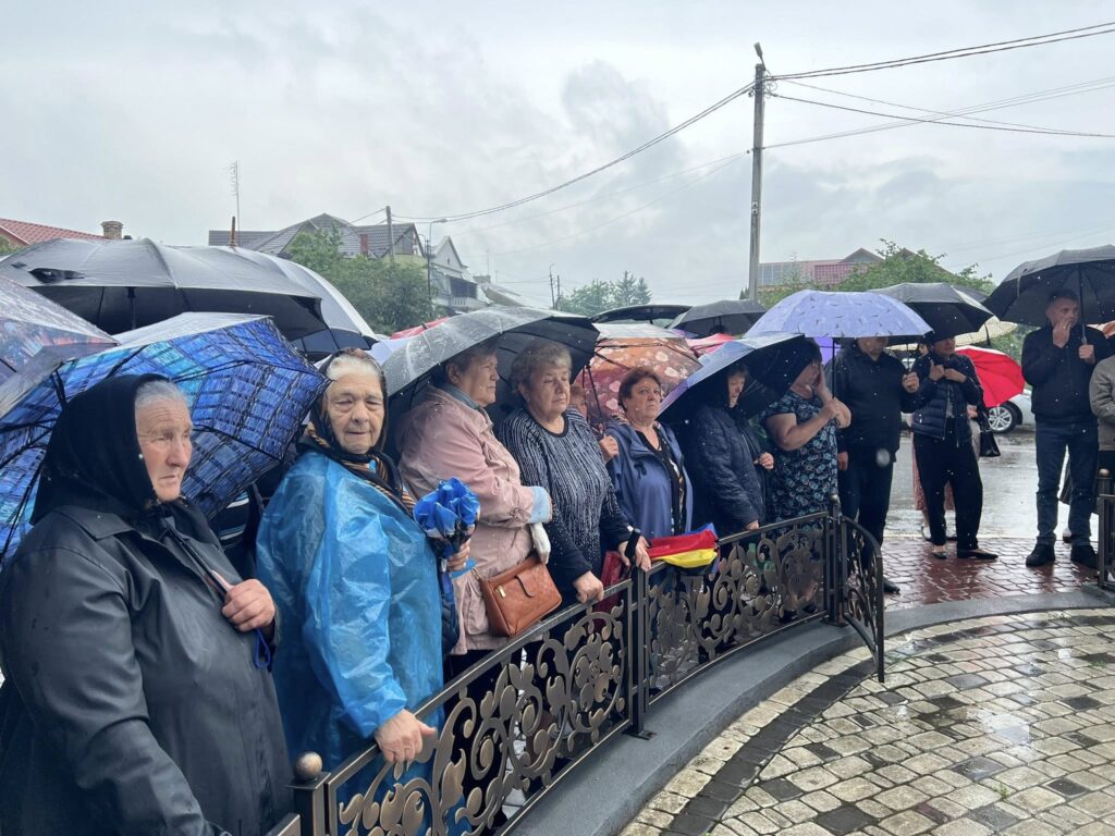 Люди під парасольками стоять під дощем на вулиці.