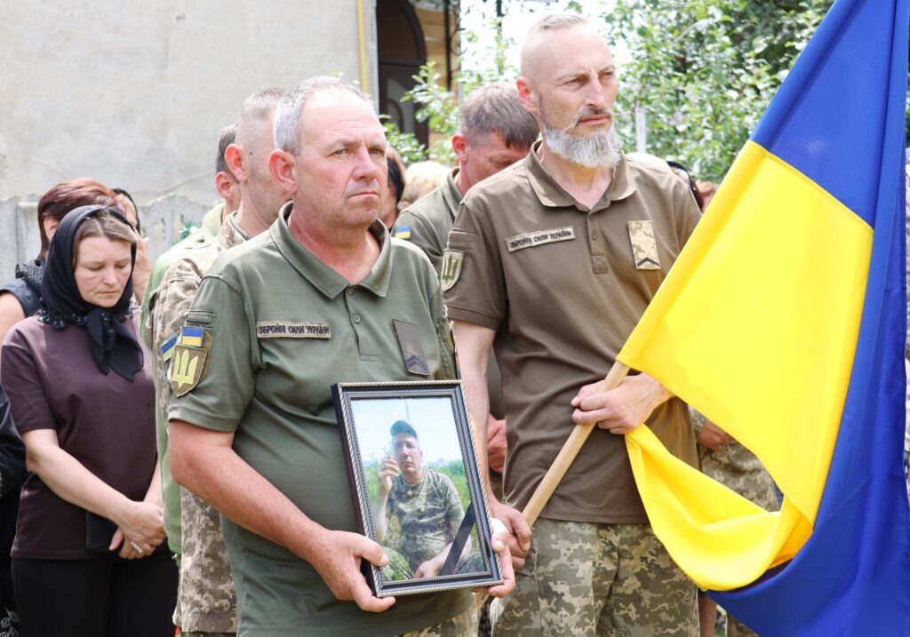 Вшанування загиблого військового з прапором України.